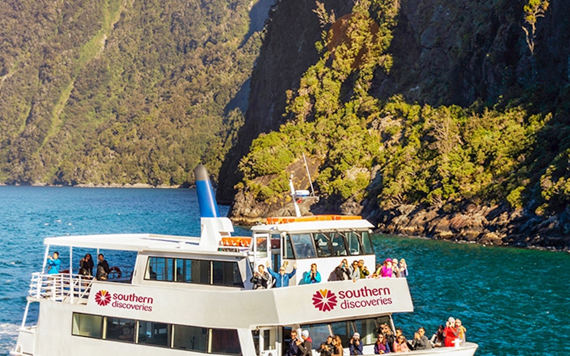 Cruise boat on Milford Sound with scenic mountain backdrop, New Zealand.