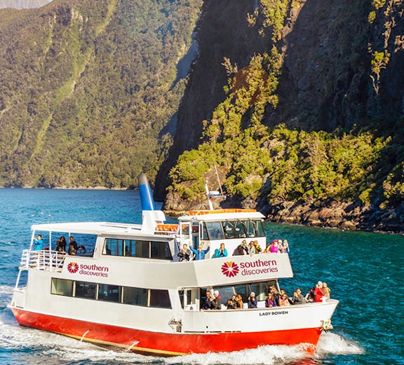 Cruise boat on Milford Sound with scenic mountain backdrop, New Zealand.
