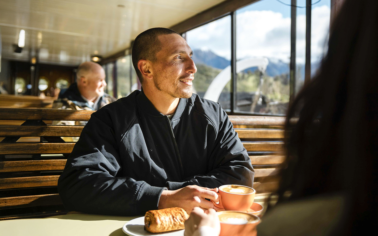 Couple enjoying coffee and pastries on a vessel with Lake Wakatipu view, Queenstown.