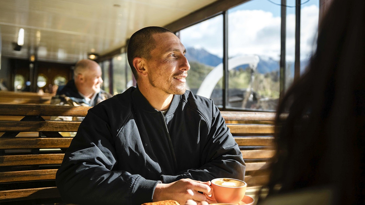 Couple enjoying coffee and pastries on a vessel with Lake Wakatipu view, Queenstown.