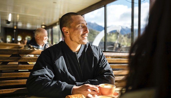 Couple enjoying coffee and pastries on a vessel with Lake Wakatipu view, Queenstown.