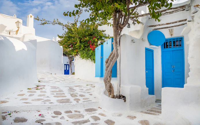 Whitewashed alley with blue doors and windows in Mykonos, Greece.