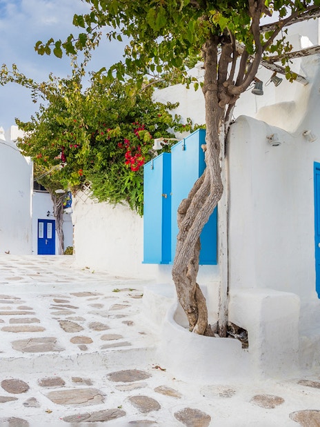 Whitewashed alley with blue doors and windows in Mykonos, Greece.