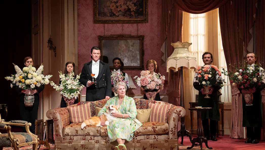 Elegant room with a woman on a sofa holding a dog, surrounded by people with flower arrangements, related to Backstairs Billy.