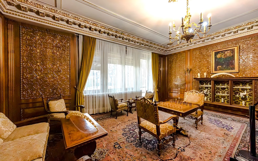 Interior of Ceaușescu Mansion in Bucharest with ornate wood paneling and vintage furniture.