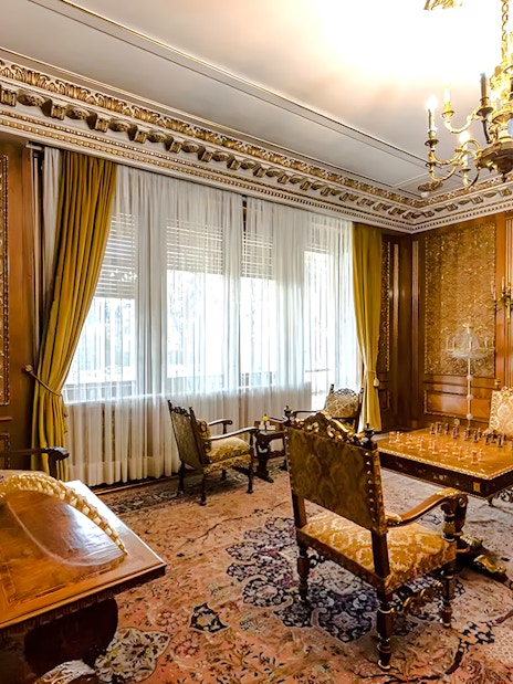 Interior of Ceaușescu Mansion in Bucharest with ornate wood paneling and vintage furniture.