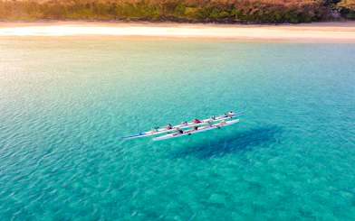 Outrigger canoe on clear waters near a sandy beach, Noronha, Sao Paulo.