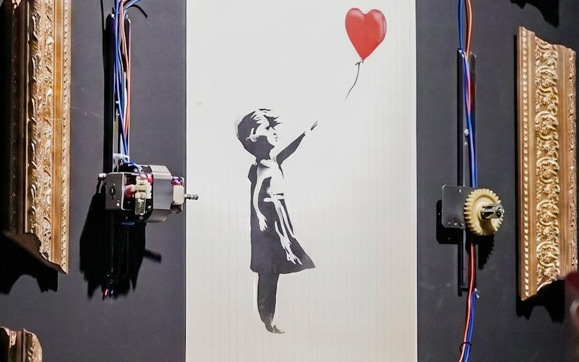 Banksy's "Girl with Red Balloon" artwork with mechanical frame at Banksy Limitless exhibit.