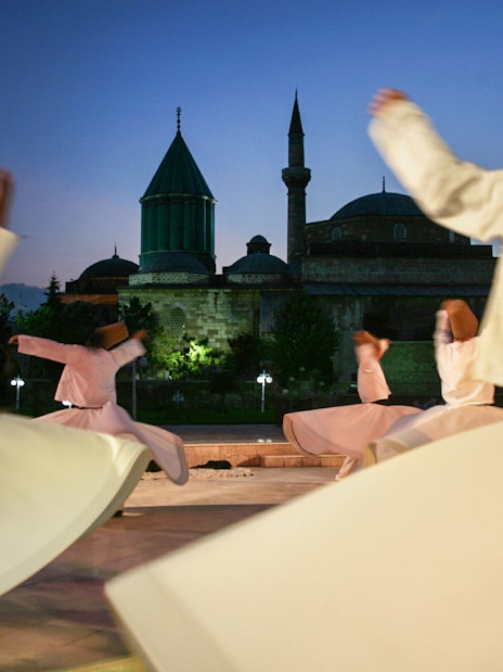 Whirling dervishes performing Mevlevi Sema in front of Istanbul mosque at dusk.