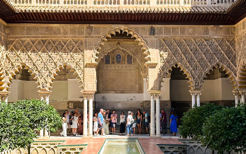Visitors exploring the intricate arches of the Alcazar of Seville on a guided tour.