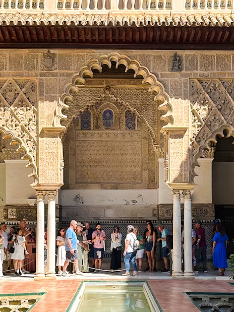 Visitors exploring the intricate arches of the Alcazar of Seville on a guided tour.