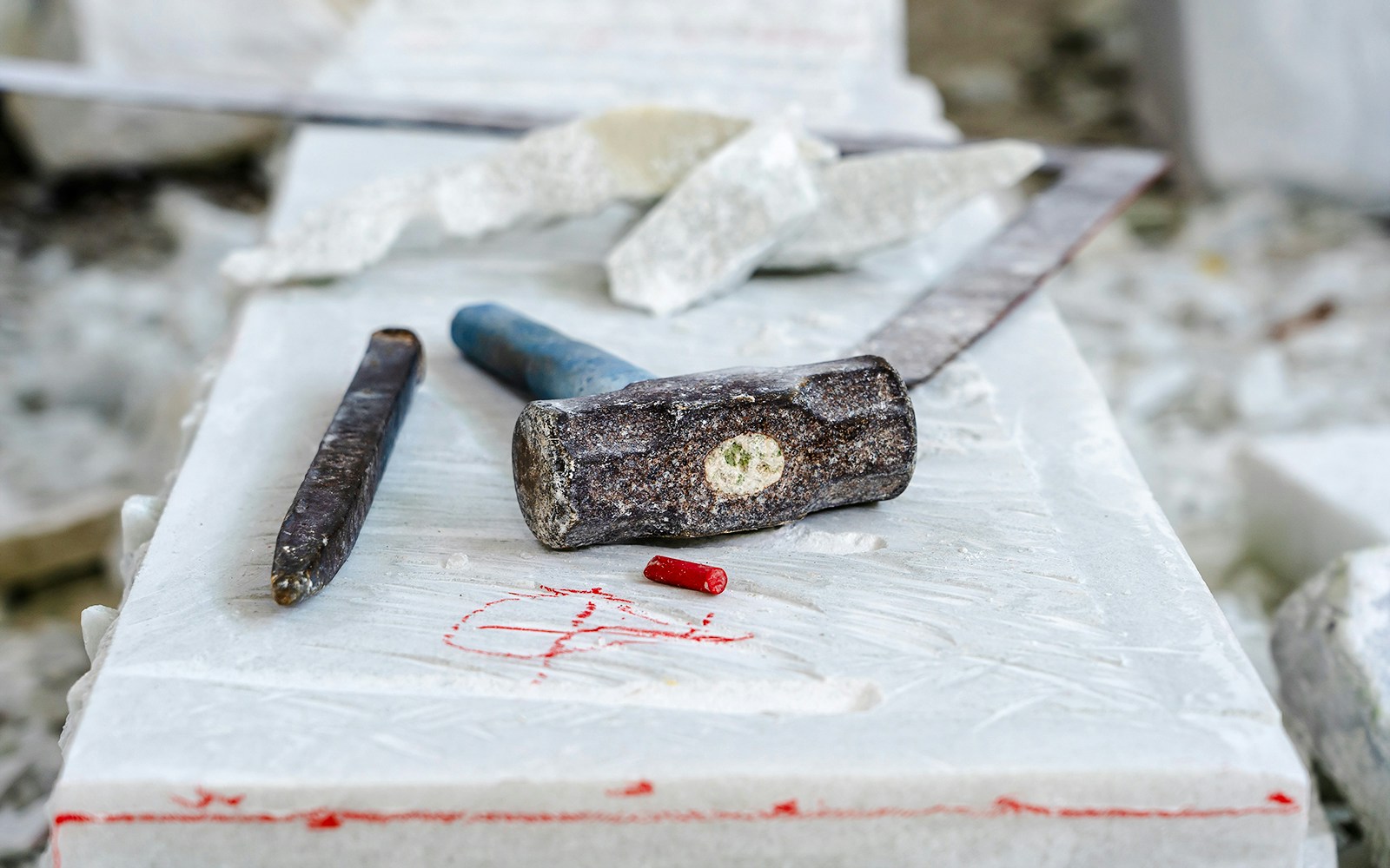Sculptor tools on a marble slab with chisel and hammer.
