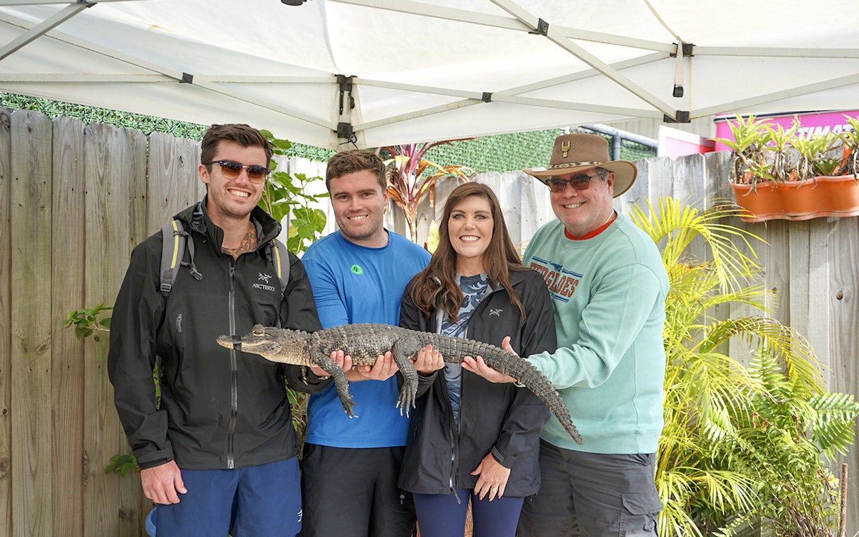 Guests holding a small alligator at Everglades Holiday Park animal encounter.