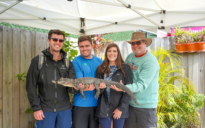 Guests holding a small alligator at Everglades Holiday Park animal encounter.