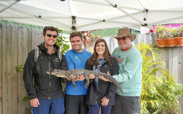 Guests holding a small alligator at Everglades Holiday Park animal encounter.