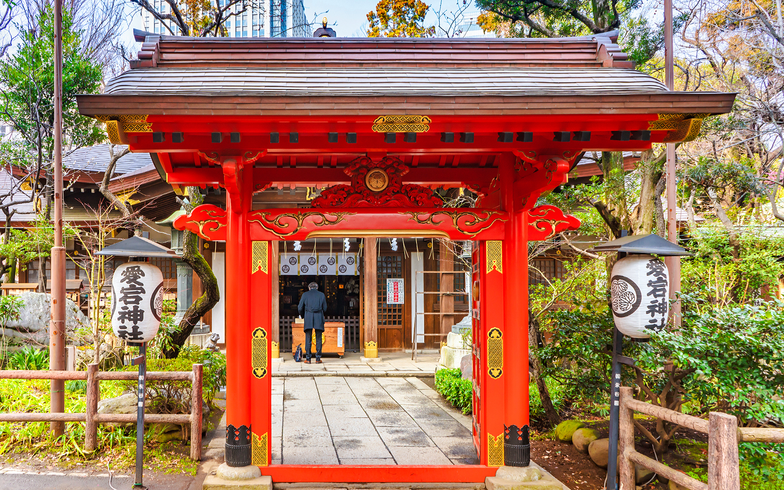 Red karamon gate at Atago Shrine, Tokyo, with a visitor approaching the entrance.