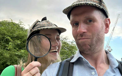 Two people in detective hats enjoying Edinburgh Murder Mystery city game.