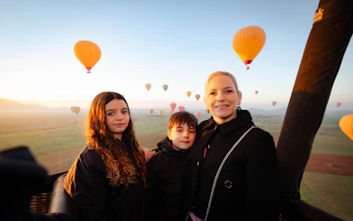 Family enjoying hot air balloon ride over Marrakech landscape.