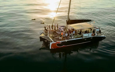 Tourists on a catamaran watching dolphins at sunrise in Mallorca.