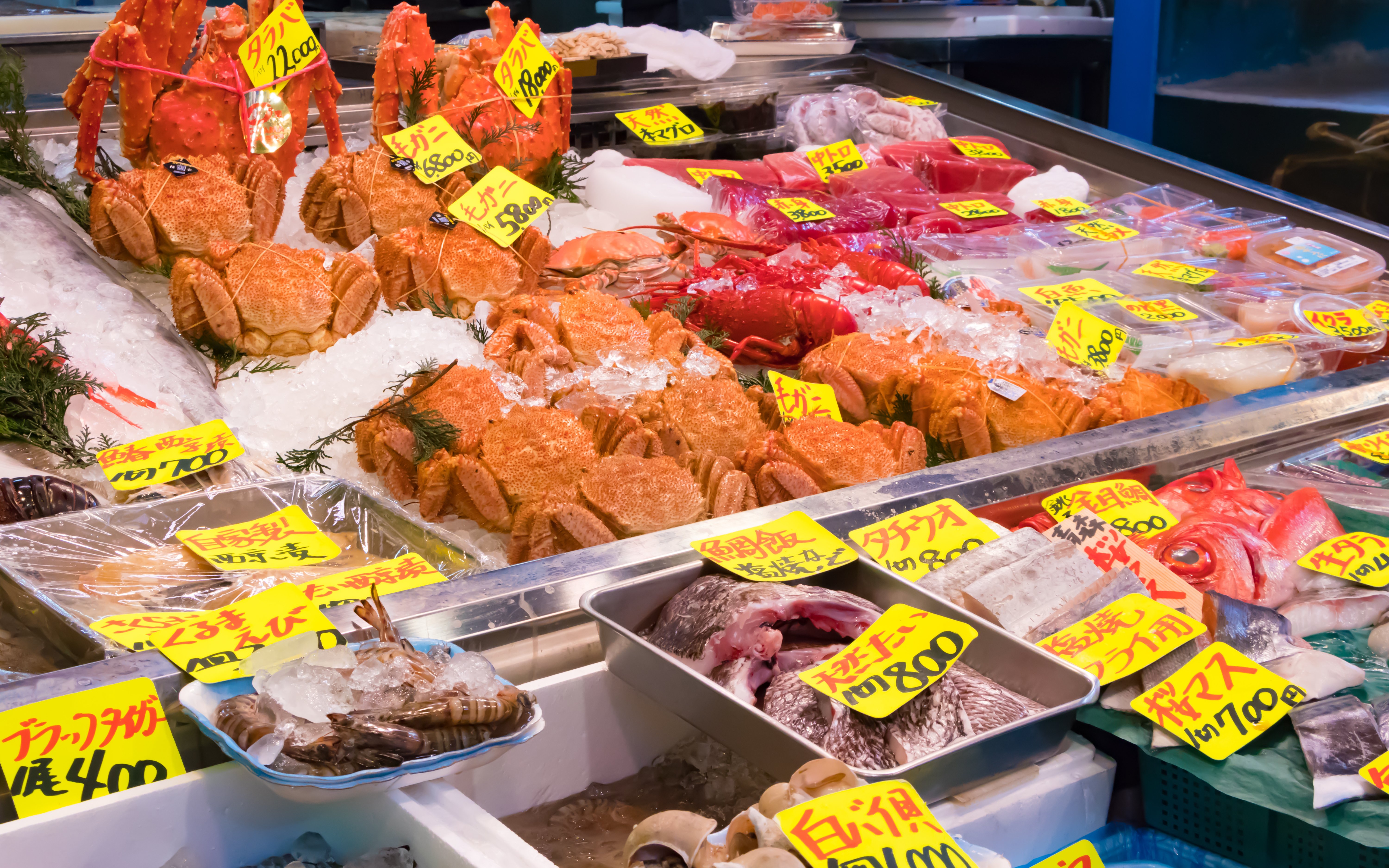 Seafood display at Tsukiji fish market in Tokyo with crabs and fish on ice.