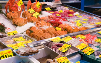 Seafood display at Tsukiji fish market in Tokyo with crabs and fish on ice.