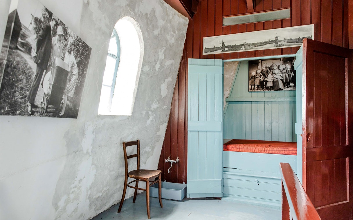 Interior of Nederwaard Museum Mill at Kinderdijk with historic photos and wooden furniture.