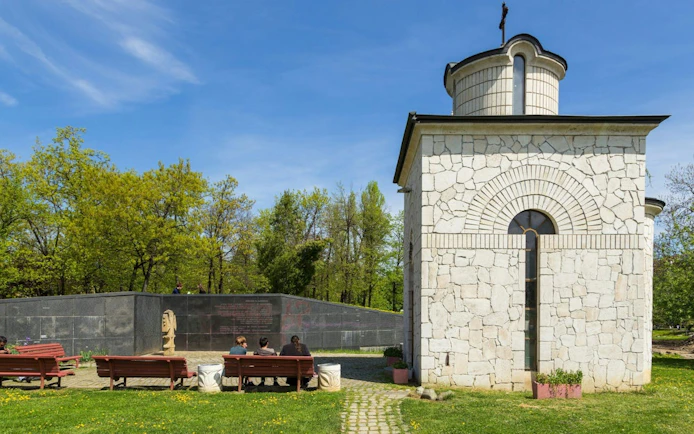 Stone building and benches in a park, part of Communist Sofia self-guided city exploration game.