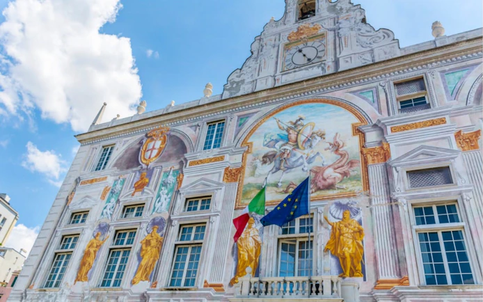 Palazzo San Giorgio facade with frescoes and flags in Genoa, Italy.