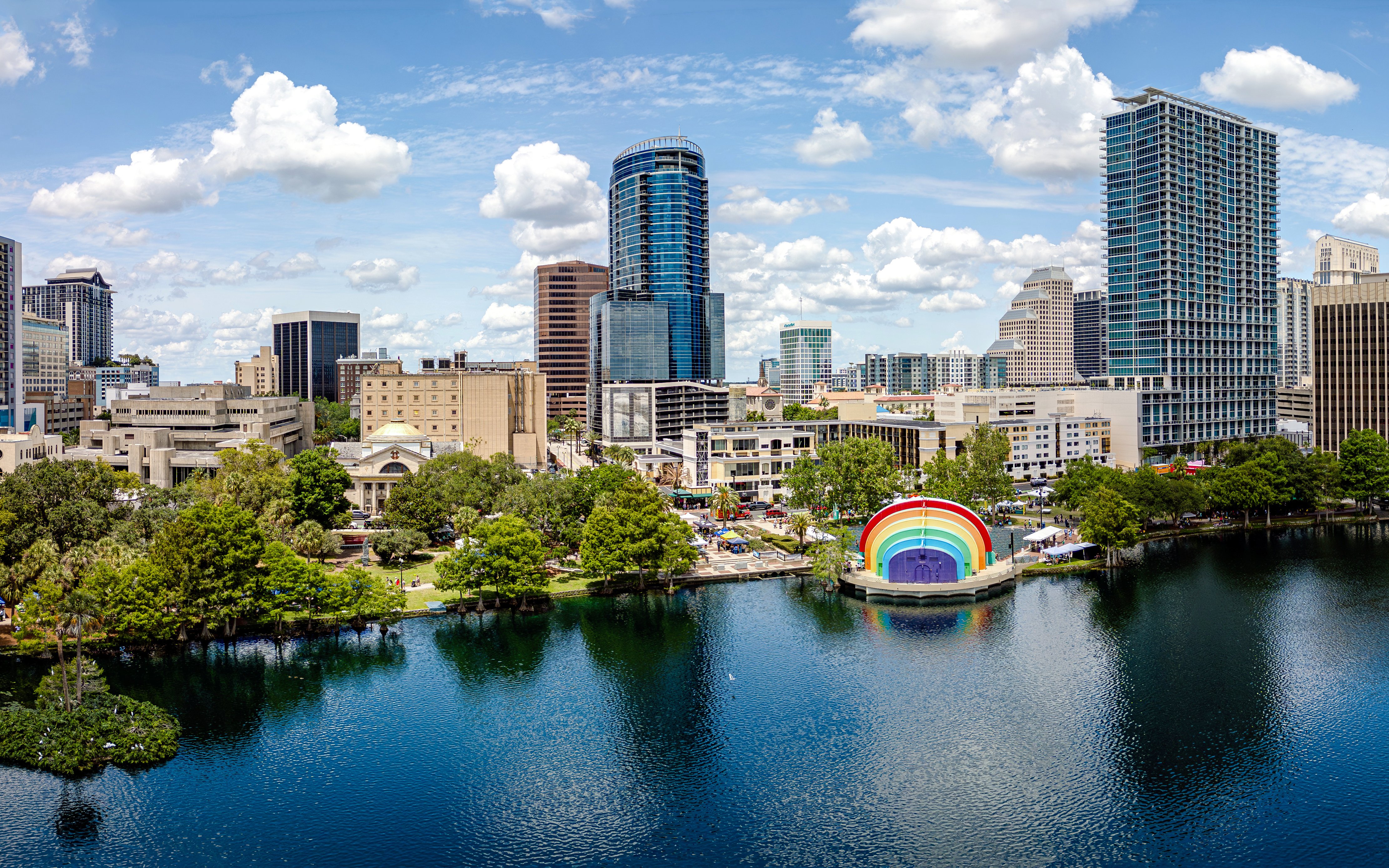 Skyline view of Lake Eola Park in Orlando with a rainbow amphitheater and surrounding buildings.