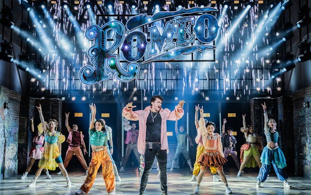 Performers on stage during a scene from the musical "& Juliet" with a "Romeo" sign above.