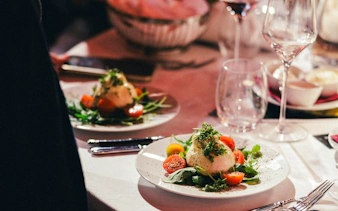 Dinner setting at The Mirage show, featuring a salad with burrata and tomatoes, Vienna.