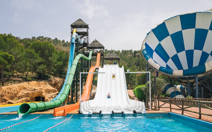 Water slides at Aqualandia Benidorm with riders descending into a pool.