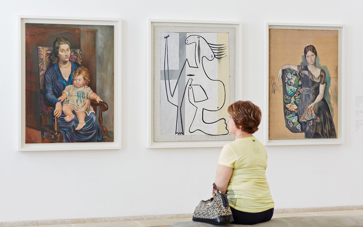 Visitor observing Pablo Picasso paintings in a gallery.