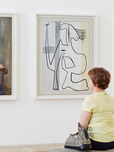 Visitor observing Pablo Picasso paintings in a gallery.