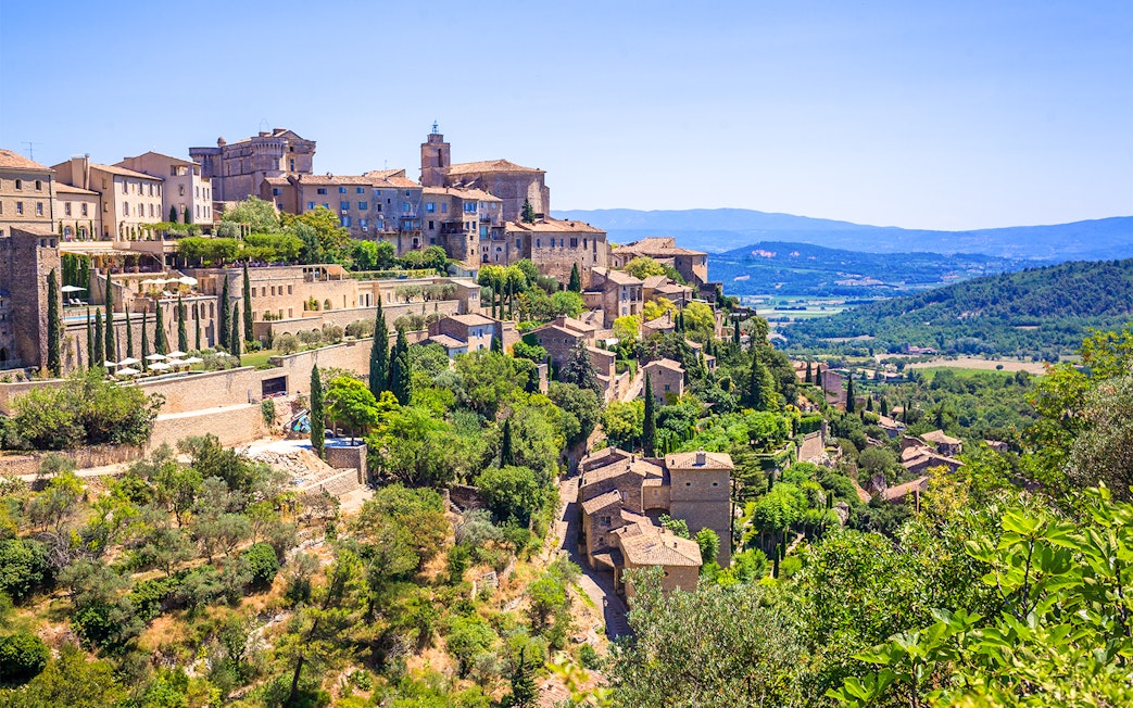 Hilltop village of Gordes in Provence with stone buildings and lush greenery.