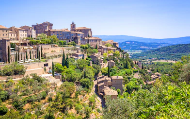 Hilltop village of Gordes in Provence with stone buildings and lush greenery.