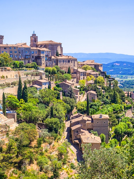 Hilltop village of Gordes in Provence with stone buildings and lush greenery.