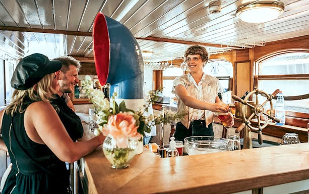 Bartender serving drinks on a Berlin bridge cruise boat.