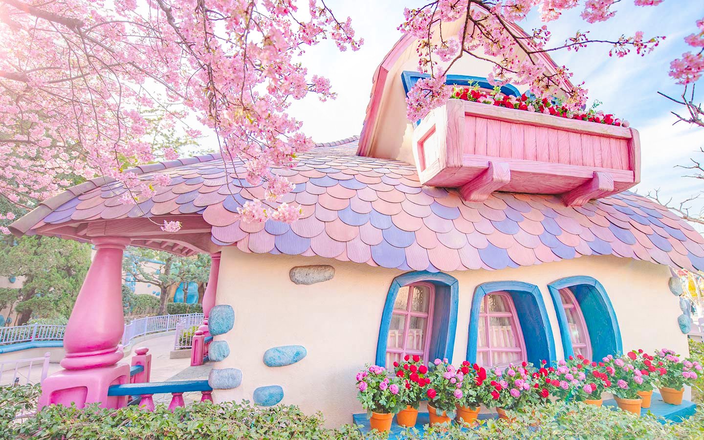 Pastel-colored building with pink roof and flowers at Tokyo Disney Resort.