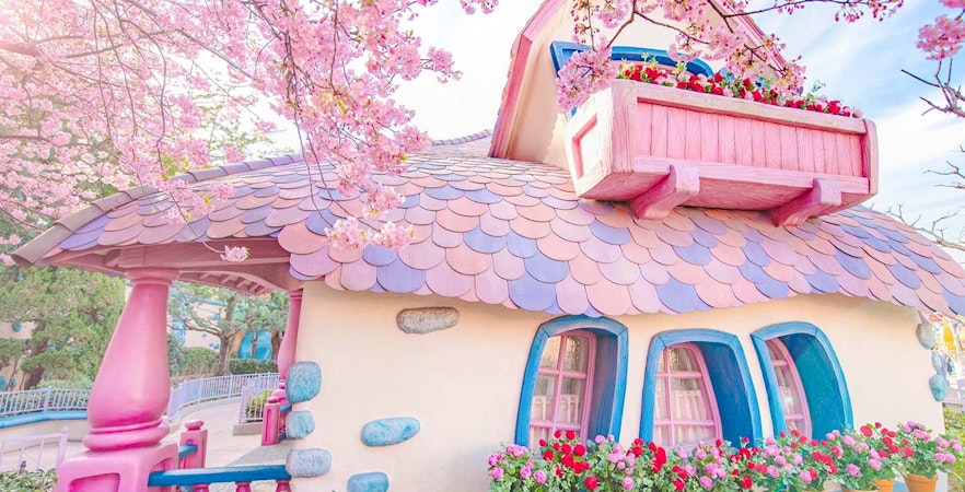 Pastel-colored building with pink roof and flowers at Tokyo Disney Resort.