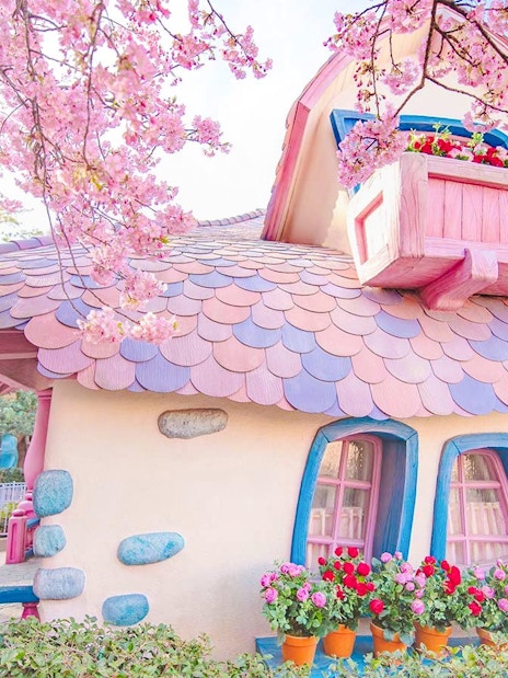 Pastel-colored building with pink roof and flowers at Tokyo Disney Resort.