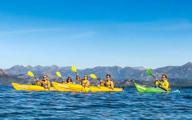 Group kayaking on a guided wildlife tour with mountain views in the background.