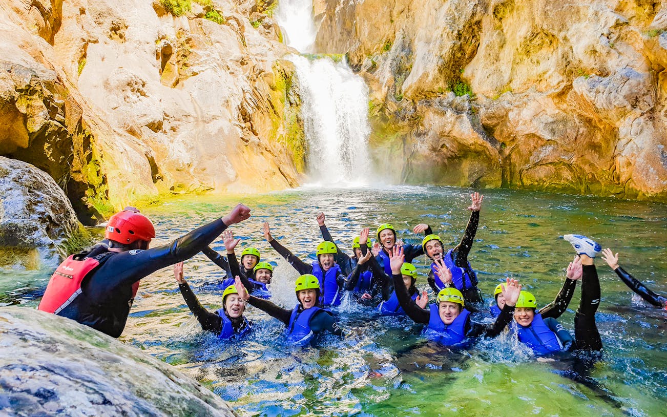 Group canyoning in Cetina River with guide, surrounded by rocky cliffs and waterfall.