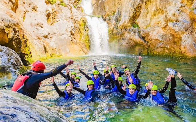 Group canyoning in Cetina River with guide, surrounded by rocky cliffs and waterfall.