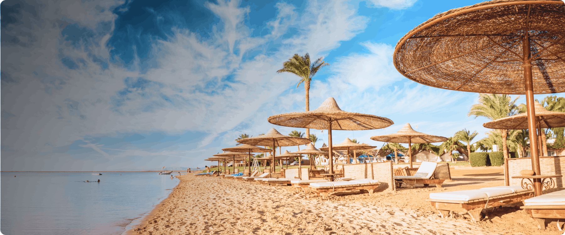 Beachfront with straw umbrellas and lounge chairs in Hurghada, Egypt.