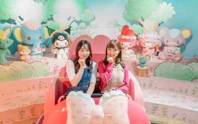 Visitors enjoying a ride at Sanrio Puroland with character figures in the background.