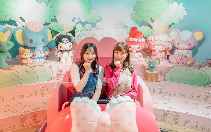 Visitors enjoying a ride at Sanrio Puroland with character figures in the background.