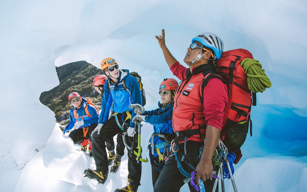 Guide leading tour group on Fox Glacier heli hike, pointing out ice formations.