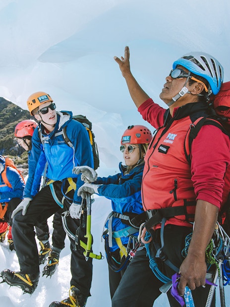 Guide leading tour group on Fox Glacier heli hike, pointing out ice formations.