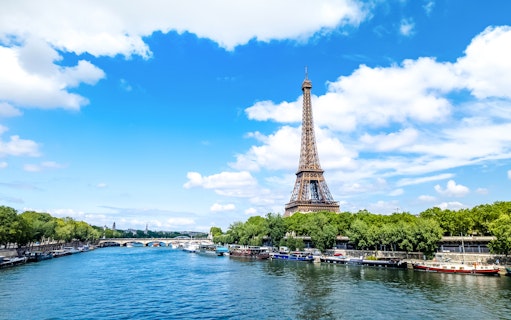 Eiffel Tower beside the Seine River in Paris with boats along the riverbank.